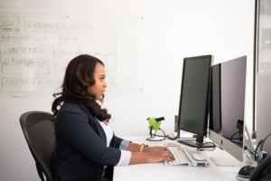 Woman sits in front of two monitors
