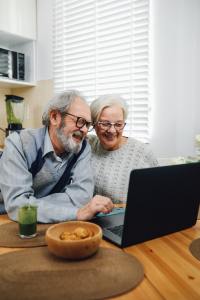 Older couple sit together looking at a laptop screen