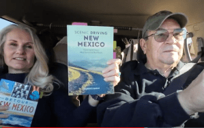 Shelley Carney and Toby Younis driving and holding up New Mexico book