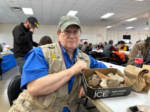 Toby Younis at the Albuquerque Gem and Mineral Show holding a box of rocks