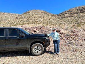 Shelley Carney at the SCRAGS claim with a rock standing by a truck