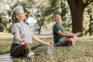 Older couple meditate outdoors